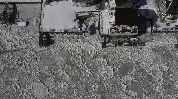 Aerial view of ice floes covering the water surface near residential houses and a wooden dock along the shoreline in Highlands New Jersey United States. Aerial view of ice floes covering the water surface near residential houses and a wooden dock along the shoreline in Highlands New Jersey United States.