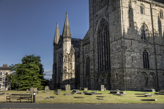 View of the historic Durham Cathedral with its intricate stone facade and surrounding graveyard featuring ancient tombstones on a sunny day in Durham England United Kingdom. View of the historic Durham Cathedral with its intricate stone facade and surrounding graveyard featuring ancient tombstones on a sunny day in Durham England United Kingdom.