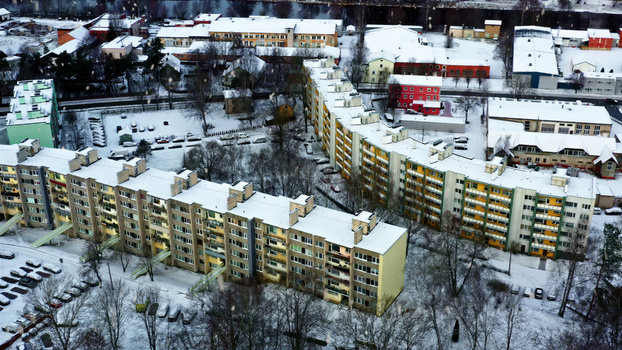 Aerial view of residential apartment buildings covered in snow with surrounding trees and parking areas in Latvia. Aerial view of residential apartment buildings covered in snow with surrounding trees and parking areas in Latvia.
