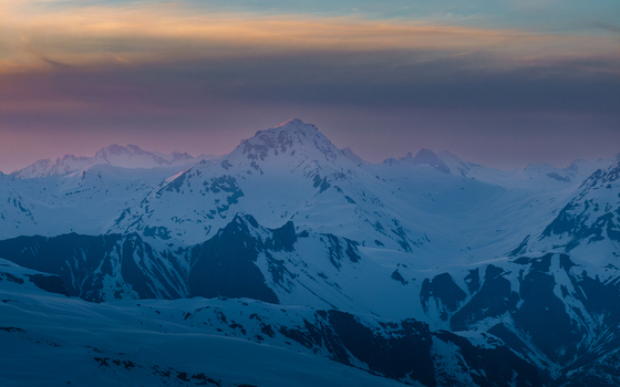 Aerial view of snow capped peaks piercing the pastel sky a serene winter landscape under a soft ethereal glow Val Thorens Auvergne Rh&ocirc;ne Alpes France.