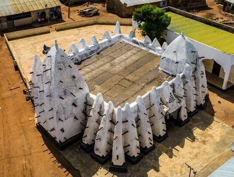 Aerial view of the historic Larabanga Mosque with its distinctive white Sudano Sahelian architecture wooden beams and flat roof in Ghana. Aerial view of the historic Larabanga Mosque with its distinctive white Sudano Sahelian architecture wooden beams and flat roof in Ghana.