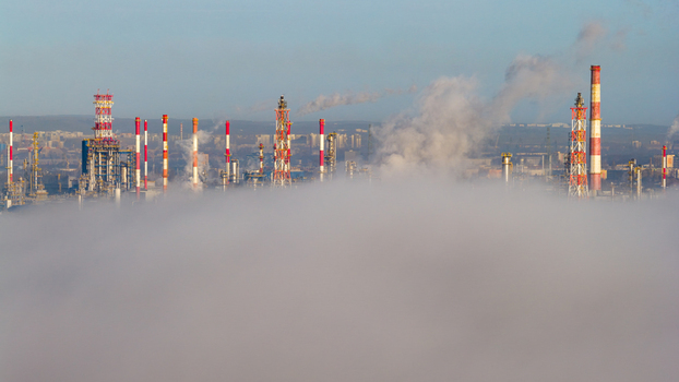 Aerial view of refinery chimneys piercing through a sea of fog their red and white stripes stark against the muted sky Gdansk Pomorskie voivodeship Poland. Aerial view of refinery chimneys piercing through a sea of fog their red and white stripes stark against the muted sky Gdansk Pomorskie voivodeship Poland.