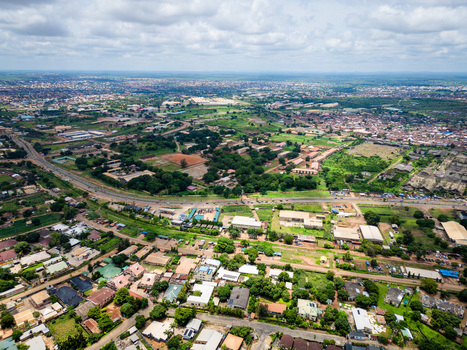 Aerial view of the Barnawa district with residential rooftops lush greenery and a major road winding through the landscape in Kaduna Kaduna Nigeria. Aerial view of the Barnawa district with residential rooftops lush greenery and a major road winding through the landscape in Kaduna Kaduna Nigeria.