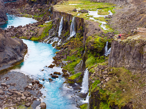 Aerial view of the turquoise river flowing through the Sigoldugljufur canyon with multiple cascading waterfalls and mossy basalt cliffs in Iceland. Aerial view of the turquoise river flowing through the Sigoldugljufur canyon with multiple cascading waterfalls and mossy basalt cliffs in Iceland.
