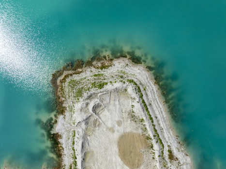 Aerial view of a turquoise lake with a gravelly peninsula and clear water in Aschheim Bavaria Germany.