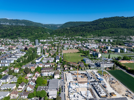 Aerial view of the urban landscape and a large construction site with cranes near the lush green hills of Biel Bienne Canton of Bern Switzerland.