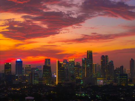 Aerial view of the Jakarta skyline featuring modern skyscrapers illuminated at sunset under a vibrant orange and red sky in Tebet Jakarta Indonesia.