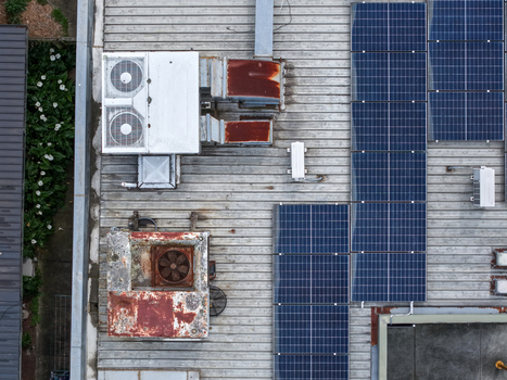 Aerial view of industrial rooftop featuring solar panels weathered HVAC units and rusted machinery in Melbourne VIC Australia.