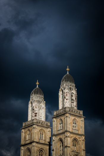 Zurich Switzerland 02 April 2023 View of the twin towers of Grossmünster piercing through a dramatic brooding sky their weathered stone facades a stark contrast to the ominous darkness above. Zurich Switzerland 02 April 2023 View of the twin towers of Grossmünster piercing through a dramatic brooding sky their weathered stone facades a stark contrast to the ominous darkness above.