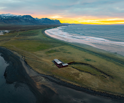 Aerial view of the historic Budir church area situated on the coast with dramatic mountains and golden sunset light in Budir Snaefellsbaer Iceland. Aerial view of the historic Budir church area situated on the coast with dramatic mountains and golden sunset light in Budir Snaefellsbaer Iceland.