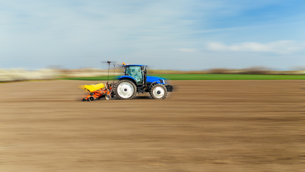 Aerial view of a blue tractor moving across the field its yellow seeder a vibrant contrast against the brown earth under a vast sky Sremska Mitrovica Vojvodina Serbia. Aerial view of a blue tractor moving across the field its yellow seeder a vibrant contrast against the brown earth under a vast sky Sremska Mitrovica Vojvodina Serbia.