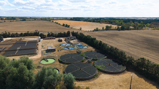 Aerial view of a wastewater treatment works with circular settling tanks and filtration beds surrounded by agricultural fields in St Neots England United Kingdom. Aerial view of a wastewater treatment works with circular settling tanks and filtration beds surrounded by agricultural fields in St Neots England United Kingdom.