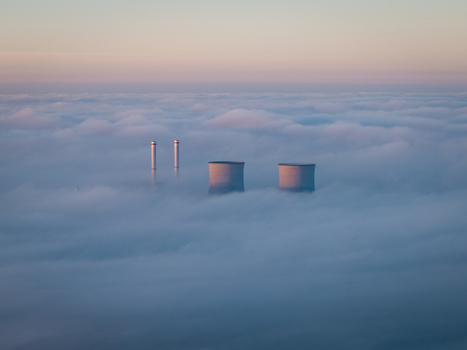 Aerial view of RWE Clauscentrale power plant cooling towers and chimneys emerging from a thick layer of morning fog under a soft sky Maasbracht Limburg Netherlands. Aerial view of RWE Clauscentrale power plant cooling towers and chimneys emerging from a thick layer of morning fog under a soft sky Maasbracht Limburg Netherlands.
