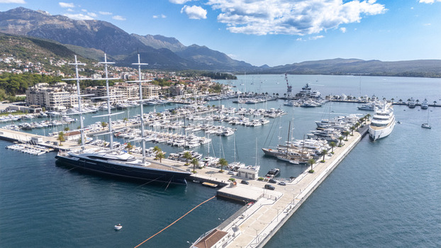 Aerial view of Porto Montenegro marina filled with luxury yachts and a large sailing vessel set against the backdrop of coastal mountains in Tivat Tivat Municipality Montenegro. Aerial view of Porto Montenegro marina filled with luxury yachts and a large sailing vessel set against the backdrop of coastal mountains in Tivat Tivat Municipality Montenegro.