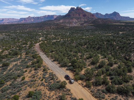 Aerial view of an SUV pulling a teardrop camper trailer on a dirt road on Gooseberry Mesa with Zion National Park in the background Hurricane Utah United States. Aerial view of an SUV pulling a teardrop camper trailer on a dirt road on Gooseberry Mesa with Zion National Park in the background Hurricane Utah United States.