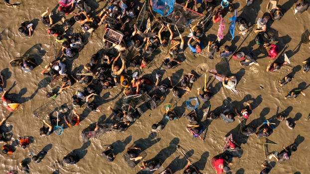 Aerial view of people fishing with nets and baskets in a muddy area in Kalikotes Central Java Indonesia.