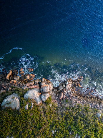 Aerial view of the rugged coastline featuring granite boulders crashing waves and coastal vegetation at Emu Point Western Australia Australia. Aerial view of the rugged coastline featuring granite boulders crashing waves and coastal vegetation at Emu Point Western Australia Australia.
