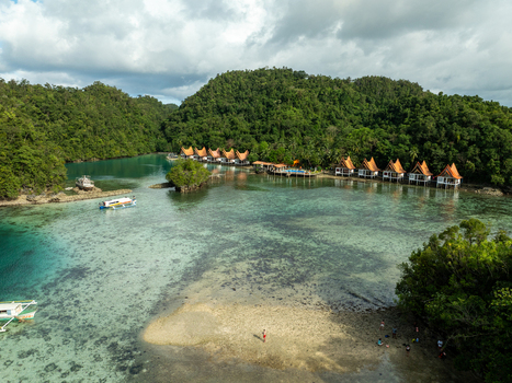 Aerial view of Bucas Grande resort featuring overwater bungalows nestled in lush green hills surrounded by clear turquoise water and small boats in Siargao Philippines. Aerial view of Bucas Grande resort featuring overwater bungalows nestled in lush green hills surrounded by clear turquoise water and small boats in Siargao Philippines.