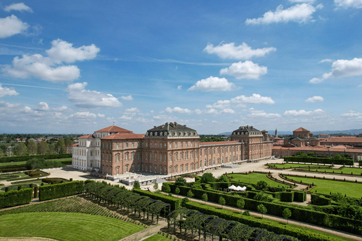 Aerial view of the majestic La Venaria Reale palace and its intricate formal gardens under a bright blue sky with scattered clouds in Venaria Reale Piemonte Italy. Aerial view of the majestic La Venaria Reale palace and its intricate formal gardens under a bright blue sky with scattered clouds in Venaria Reale Piemonte Italy.