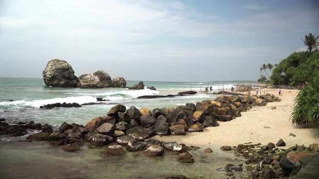 View of stilt fishermen and rocky coastline Sri Lanka.