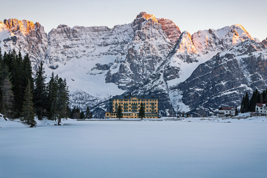 View of the historic Grand Hotel Misurina standing before the majestic snow capped peaks of the Dolomites and a frozen lake at sunset Trentino Alto Adige Italy. View of the historic Grand Hotel Misurina standing before the majestic snow capped peaks of the Dolomites and a frozen lake at sunset Trentino Alto Adige Italy.