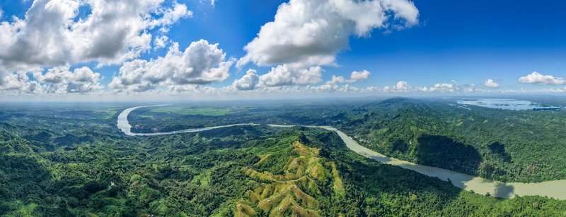 Aerial view of Shita Pahar featuring lush green hills the winding Karnaphuli River and a bright blue sky with scattered white clouds in Kaptai Chittagong Division Bangladesh. Aerial view of Shita Pahar featuring lush green hills the winding Karnaphuli River and a bright blue sky with scattered white clouds in Kaptai Chittagong Division Bangladesh.