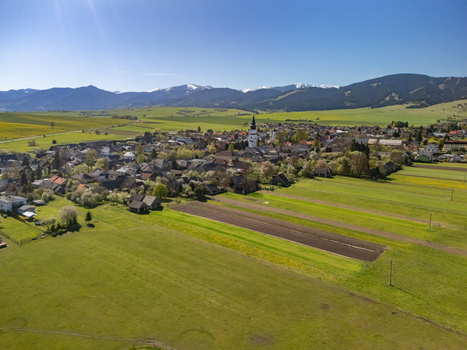 Aerial view of the historic village featuring its prominent church tower and traditional houses nestled among green fields in Partizanska Lupca Zilina Region Slovakia.