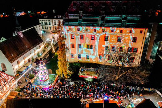 Forchheim Germany 20 December 2025 Aerial view of the Weihnachtsmarkt Forchheim at night with light projections on the Kaiserpfalz building a Christmas pyramid and crowds.