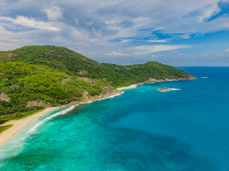 Aerial view of lush green hills meeting the turquoise ocean along the sandy shores of Police Bay Mahe Island Seychelles. Aerial view of lush green hills meeting the turquoise ocean along the sandy shores of Police Bay Mahe Island Seychelles.