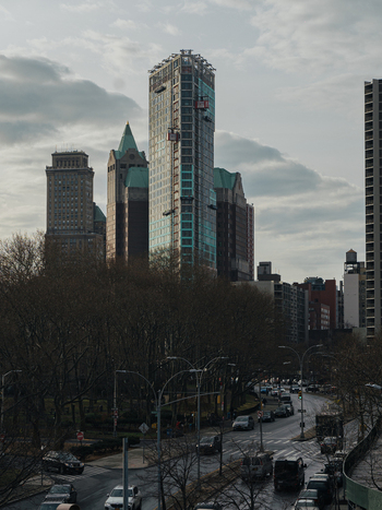 View of the Brooklyn skyline featuring modern skyscrapers and historic architecture rising above bare trees and city streets in Kings County New York United States.