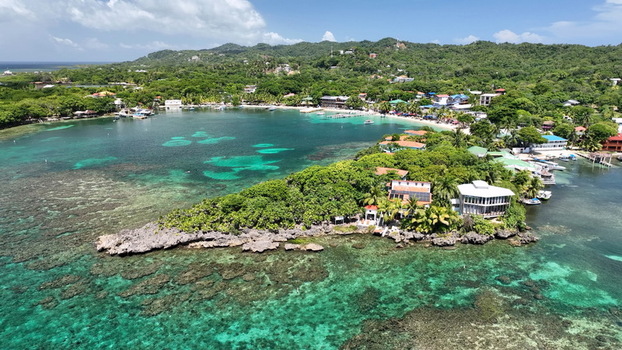 Aerial view of West End featuring lush tropical vegetation turquoise coral reef waters boats and coastal buildings in West End Bay Islands Department Honduras.