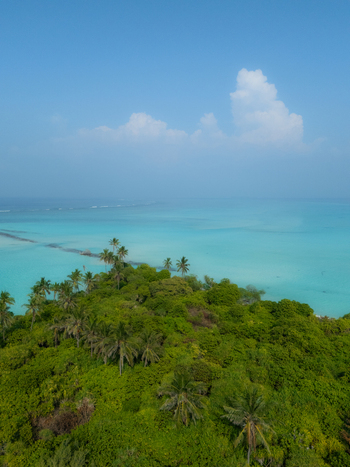 Aerial view of lush greenery meets the turquoise sea a bridge connecting lands under the vast blue sky Thuraakunu Thiladhunmathee Uthuruburi Maldives. Aerial view of lush greenery meets the turquoise sea a bridge connecting lands under the vast blue sky Thuraakunu Thiladhunmathee Uthuruburi Maldives.