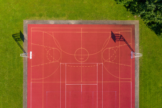 Aerial view of the red basketball court at Sport Island Forchheim with yellow markings and long shadows on green grass in Forchheim Bavaria Germany. Aerial view of the red basketball court at Sport Island Forchheim with yellow markings and long shadows on green grass in Forchheim Bavaria Germany.