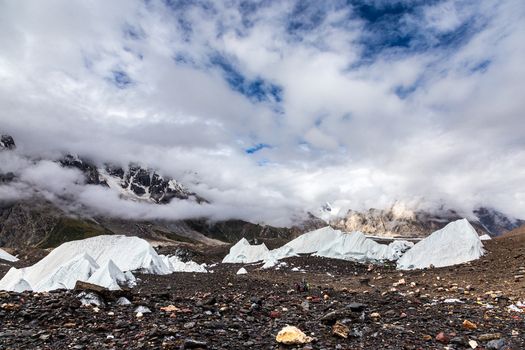 View of the rugged Baltoro Glacier with massive ice formations rocky moraine and dramatic clouds clinging to the surrounding high mountain peaks in Baltoro Gilgit Baltistan Pakistan.