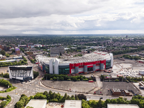 Aerial view of Old Trafford stadium home of Manchester United surrounded by urban infrastructure roads and parking lots in Stretford England United Kingdom.