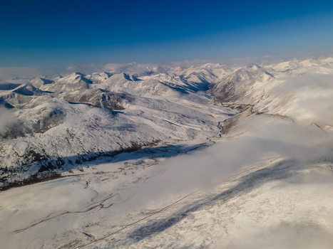 Aerial view of Babusar Pass with snow covered mountain peaks and a winding road through the valley under a clear blue sky Babusar KPK Pakistan.