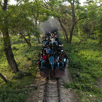 Dhaka Bangladesh 27 March 2026 Aerial view of a train densely packed with people cutting through a verdant landscape smoke billowing against a backdrop of lush greenery. Dhaka Bangladesh 27 March 2026 Aerial view of a train densely packed with people cutting through a verdant landscape smoke billowing against a backdrop of lush greenery.