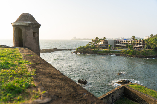 View of a historic stone watchtower on the ramparts of Galle Fort overlooking the ocean and a coastal resort in Galle Southern Province Sri Lanka.
