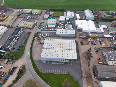 Aerial view of industrial buildings casting long shadows under the pale sky juxtaposed against the verdant fields creating a stark contrast Nantwich United Kingdom. Aerial view of industrial buildings casting long shadows under the pale sky juxtaposed against the verdant fields creating a stark contrast Nantwich United Kingdom.