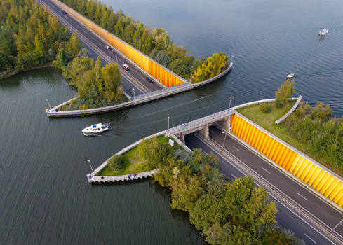Aerial view of Aquaduct Veluwemeer showing a road passing under the water with a boat navigating the canal above in Harderwijk Gelderland Netherlands.