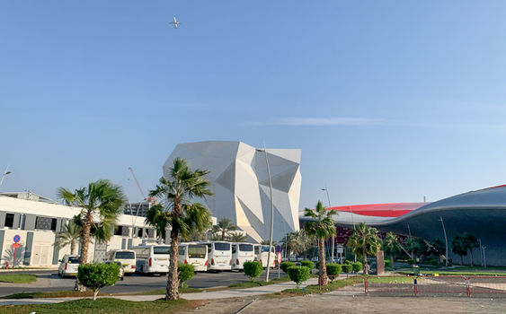 View of the geometric architecture of Ferrari World Yas Island with palm trees and parked buses in the foreground in Abu Dhabi Abu Dhabi United Arab Emirates. View of the geometric architecture of Ferrari World Yas Island with palm trees and parked buses in the foreground in Abu Dhabi Abu Dhabi United Arab Emirates.