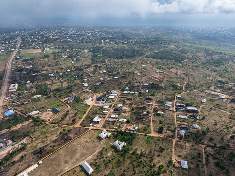Aerial view of scattered settlements and winding roads amidst a tapestry of earthy brown and vibrant green landscapes under a soft overcast sky Elu Abia Nigeria. Aerial view of scattered settlements and winding roads amidst a tapestry of earthy brown and vibrant green landscapes under a soft overcast sky Elu Abia Nigeria.