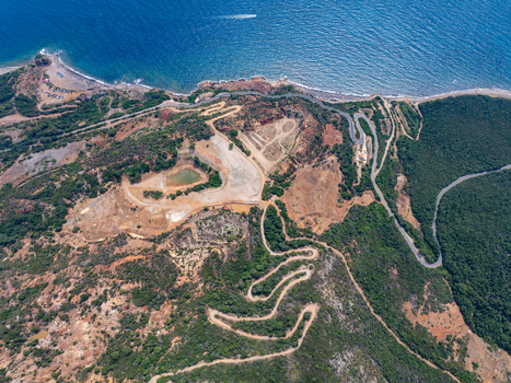 Aerial view of the historic iron mine area with reddish soil winding roads and the Laghetto delle conche near the coast in Rio Marina Toscana Italy.