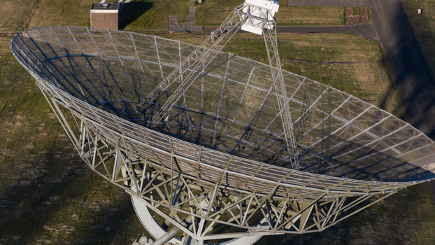 Aerial view of the Westerbork Synthesis Radio Telescope showing the massive parabolic dish and intricate metal framework over green fields Zwiggelte Drenthe Netherlands. Aerial view of the Westerbork Synthesis Radio Telescope showing the massive parabolic dish and intricate metal framework over green fields Zwiggelte Drenthe Netherlands.