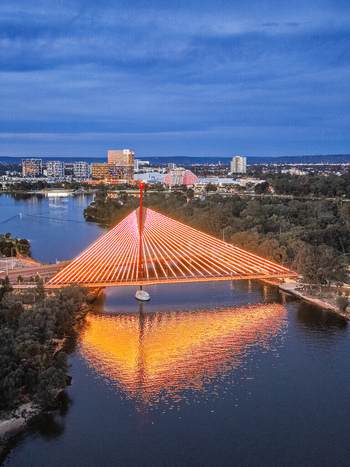 Aerial view of the illuminated Boorloo Bridge spanning the Swan River with the city skyline in the background at dusk East Perth Western Australia Australia.