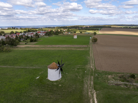 Aerial view of the historic Regi Szelmalom windmills situated in the green fields near the village with cultivated farmland and a blue sky with clouds Tes Hungary. Aerial view of the historic Regi Szelmalom windmills situated in the green fields near the village with cultivated farmland and a blue sky with clouds Tes Hungary.