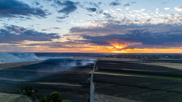 Aerial view of a field with smoke rising from a fire at sunset with a road cutting through the landscape near Sremska Mitrovica Vojvodina Serbia. Aerial view of a field with smoke rising from a fire at sunset with a road cutting through the landscape near Sremska Mitrovica Vojvodina Serbia.