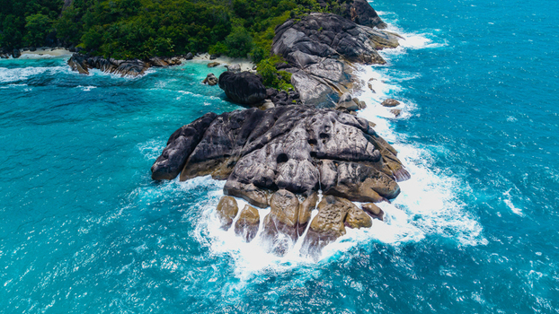 Aerial view of the rocky coastline and turquoise waters near Anse Soleil Beachcomber Hotel in Mahe Baie Lazare Seychelles.