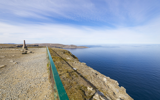 View of the vast deep blue sea meeting the stark rocky cliffs under a bright expansive sky a serene and majestic landscape Nordkapp Finnmark Norway. View of the vast deep blue sea meeting the stark rocky cliffs under a bright expansive sky a serene and majestic landscape Nordkapp Finnmark Norway.