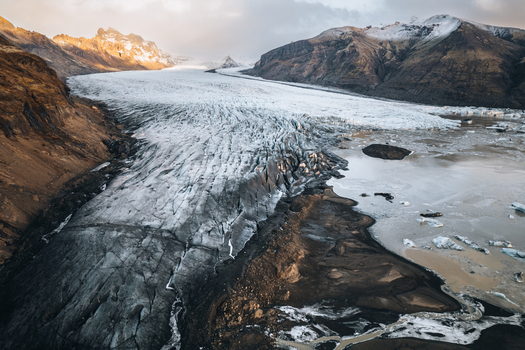 Aerial view of the massive Skaftafellsjokull glacier tongue with deep crevasses and icebergs in the lagoon surrounded by rugged mountains Skaftafell Sveitarfelagid Hornafjordur Iceland. Aerial view of the massive Skaftafellsjokull glacier tongue with deep crevasses and icebergs in the lagoon surrounded by rugged mountains Skaftafell Sveitarfelagid Hornafjordur Iceland.